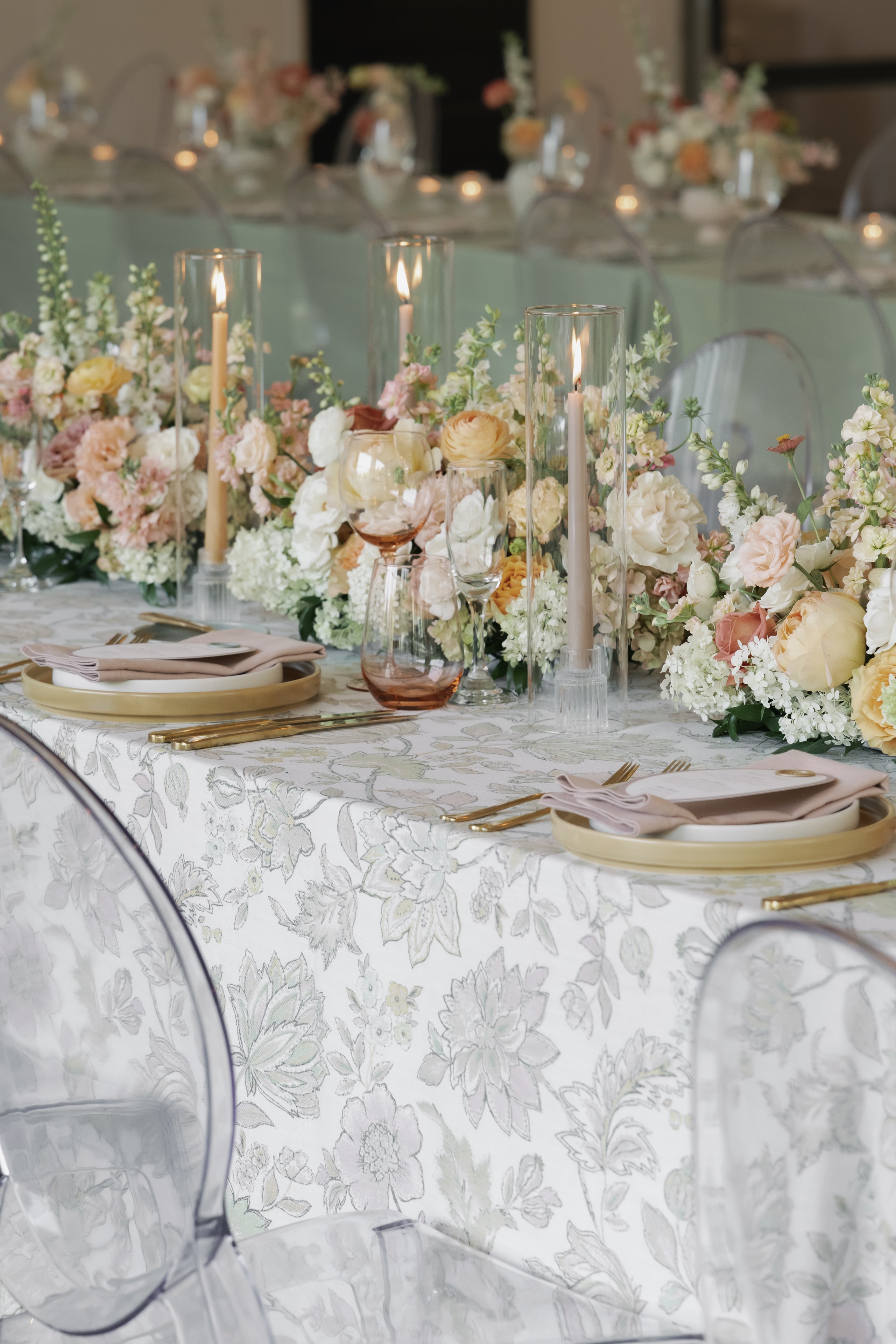 Elegant wedding reception table with lush floral runner peach roses and tapered candles
