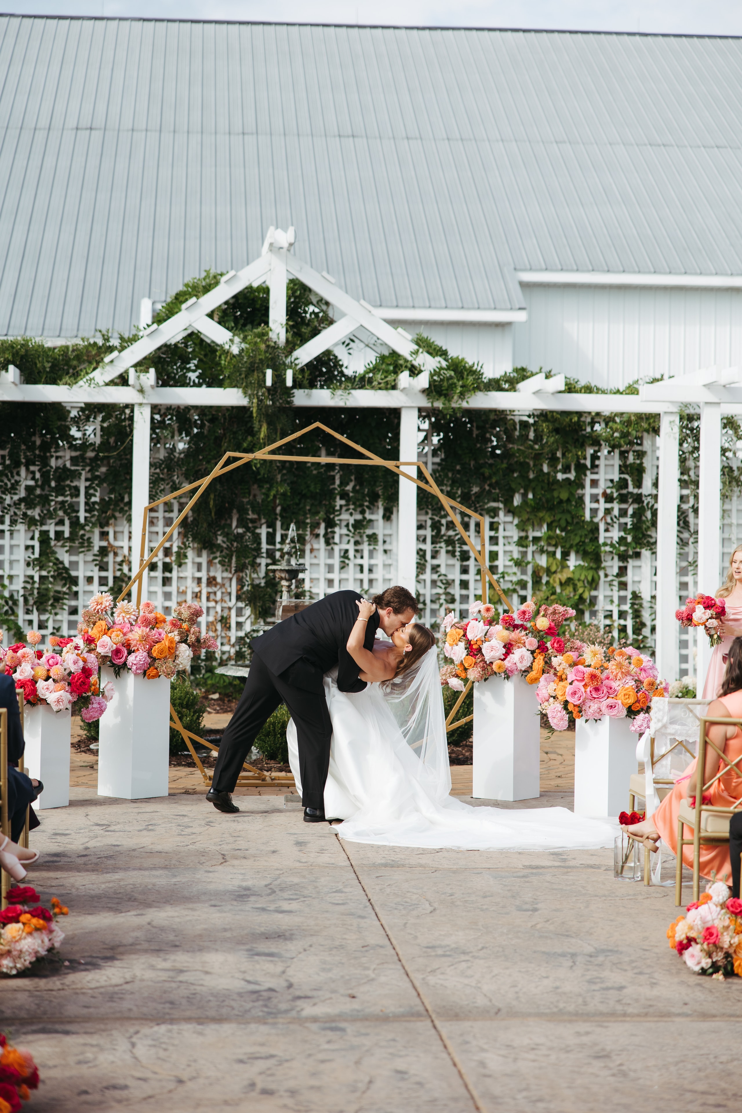 Groom dipping bride under floral arch — Equestria West