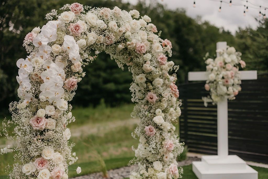 Outdoor wedding floral arch with white orchids and cream roses