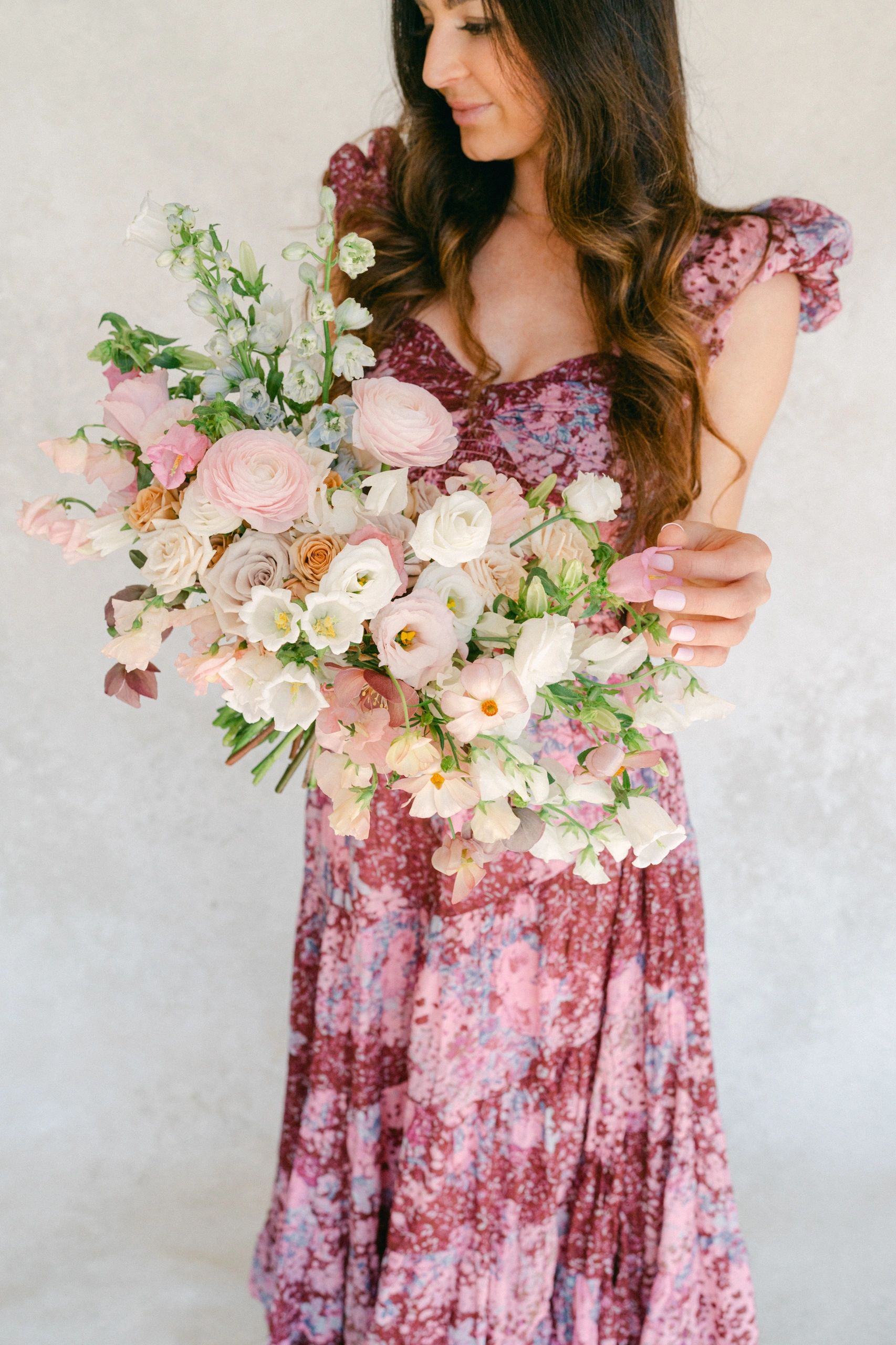 Woman in burgundy dress holding bridal bouquet of pink roses