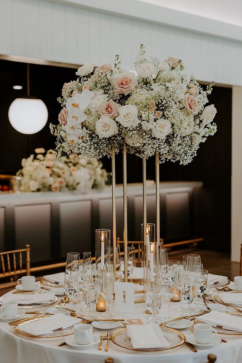 Wedding reception tall centerpiece with white orchids on gold vase