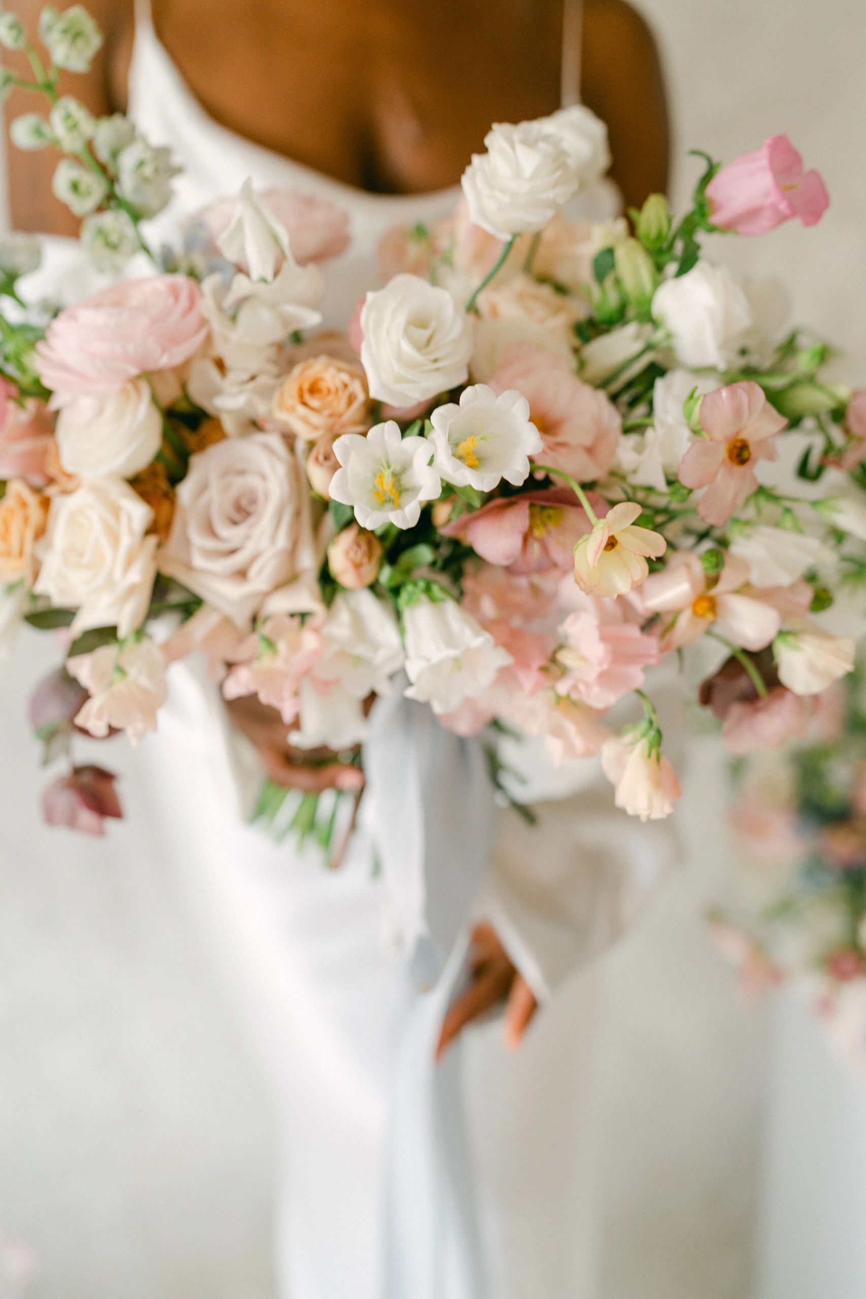 Bride in white dress holding bouquet of white roses
