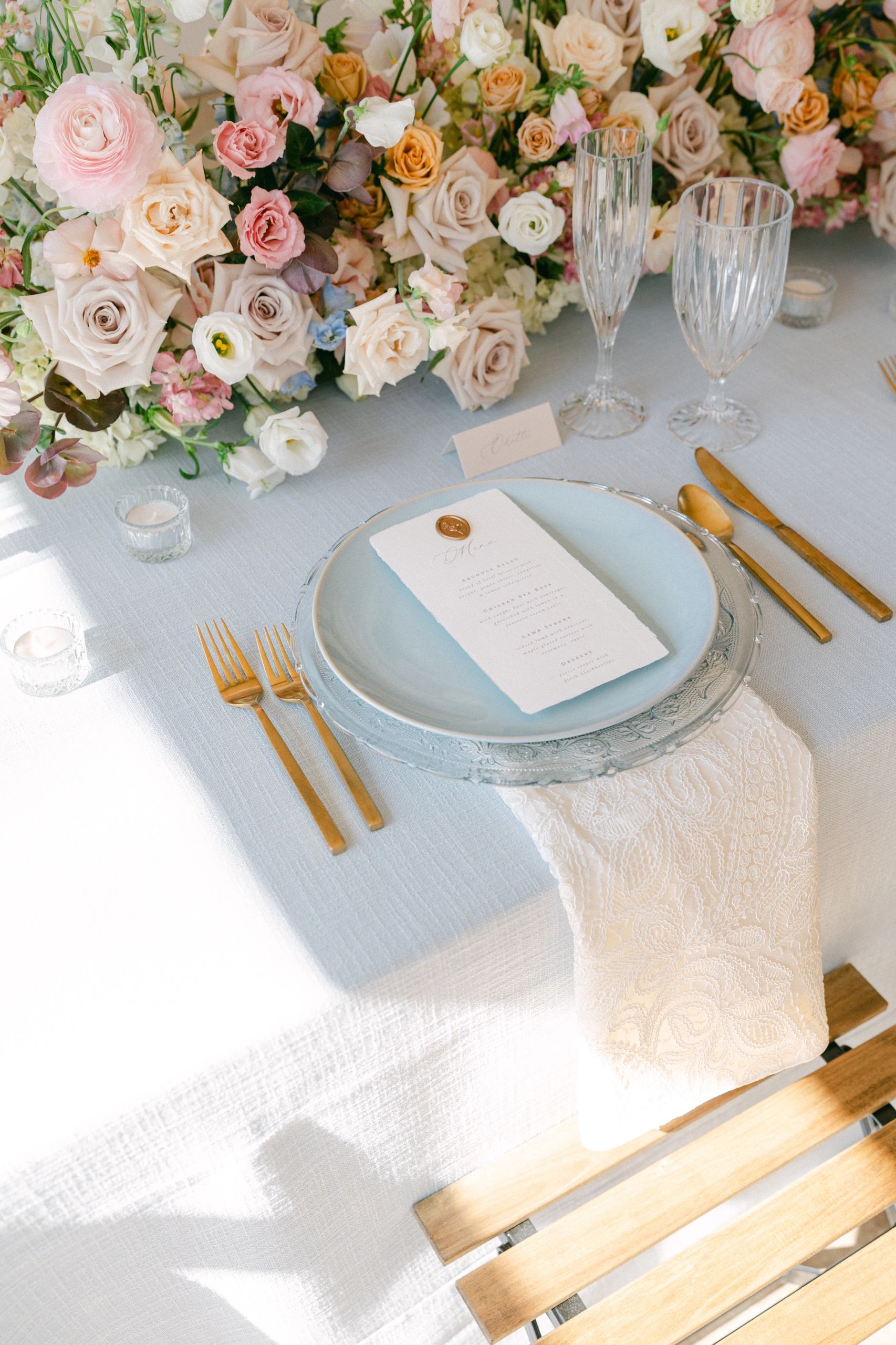Wedding table setting flat lay with blue tablecloth and gold cutlery